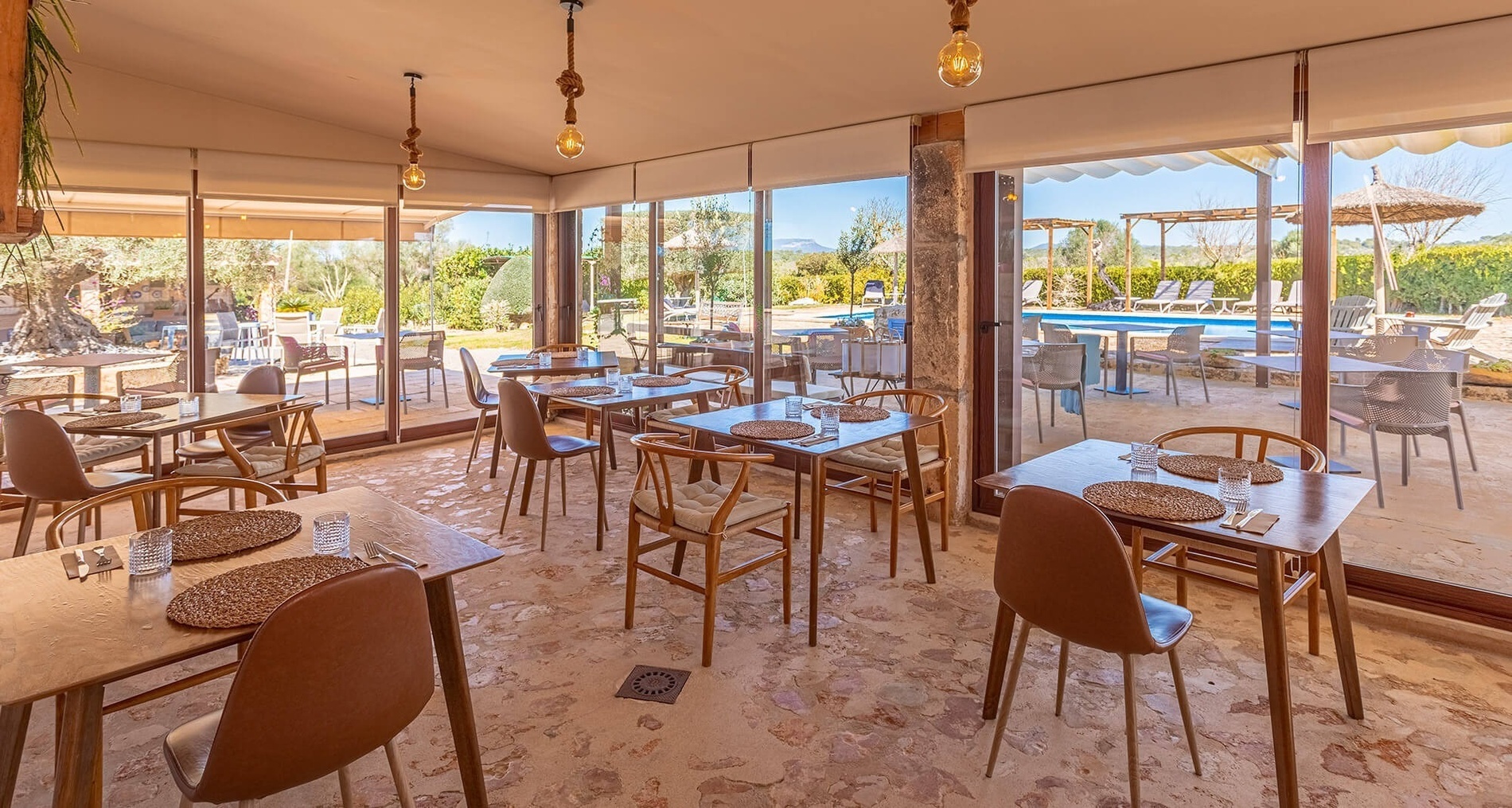 a dining room with tables and chairs and a pool in the background