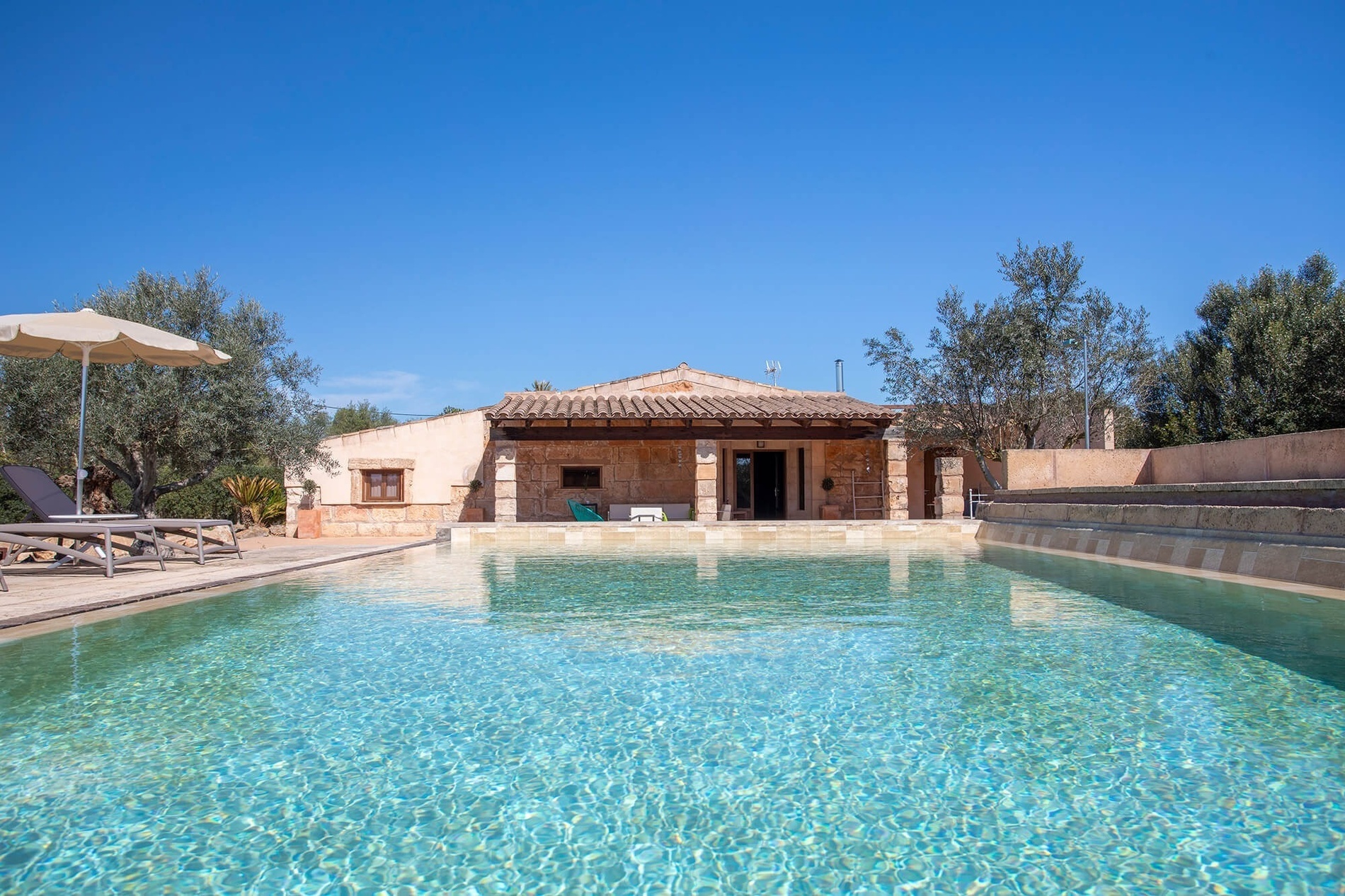 una casa de piedra con una piscina al frente=s1900