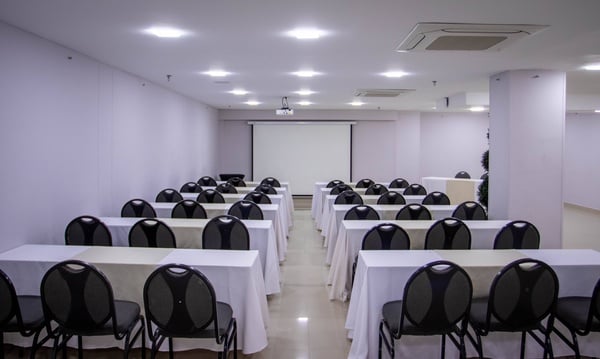 una sala de conferencias con mesas y sillas y una pantalla