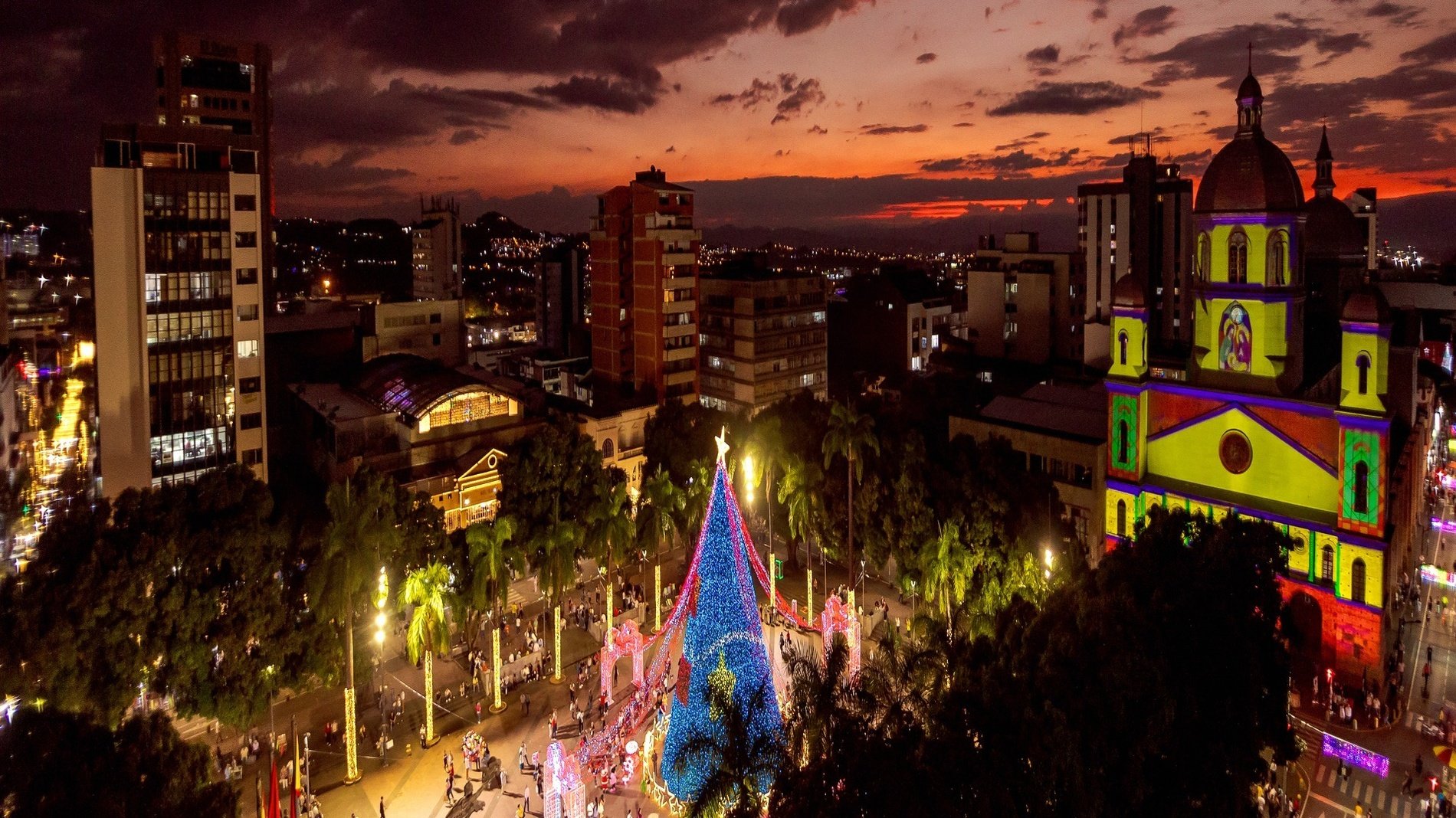 an aerial view of a city at night with a christmas tree in the foreground