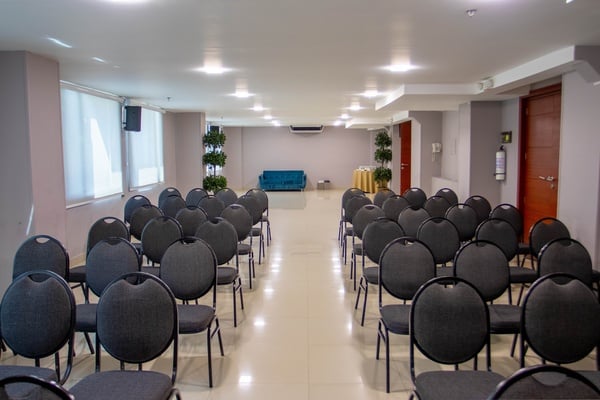 una sala de conferencias llena de sillas negras y un sofá azul