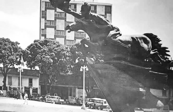 a statue of a man riding a horse in front of a building .