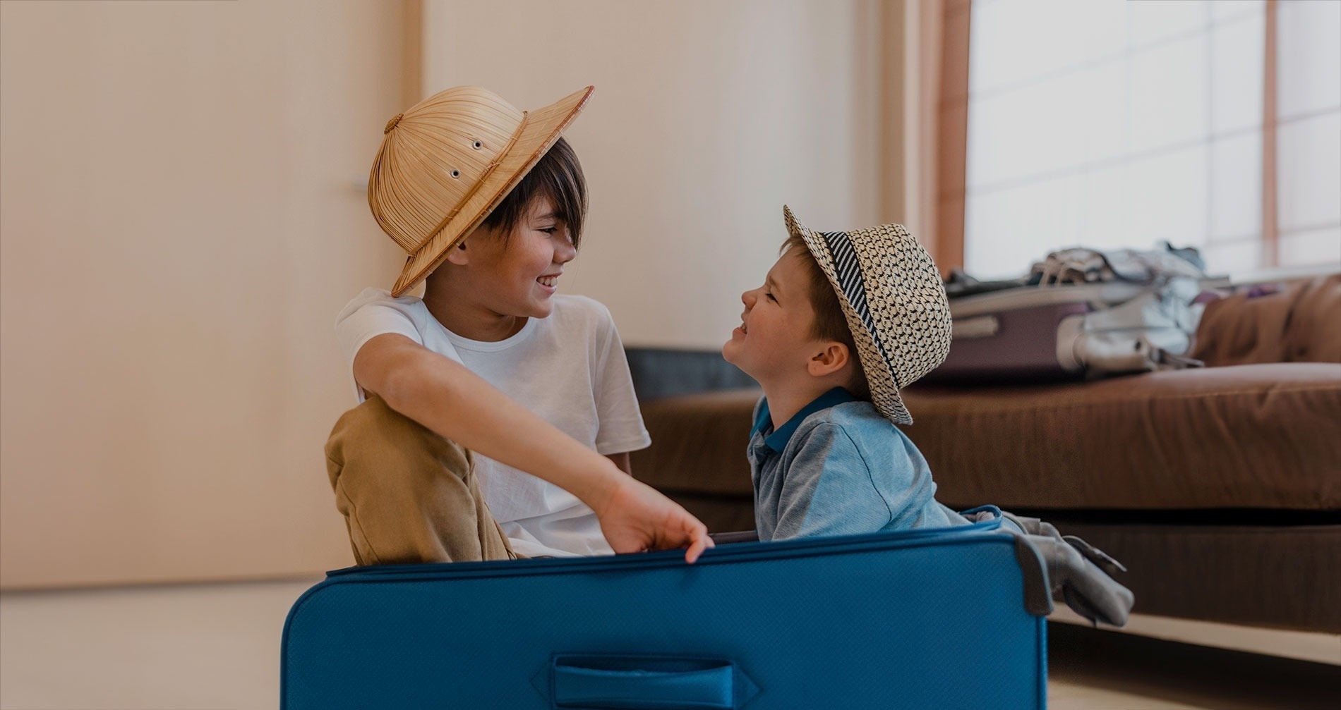 dos niños están sentados en una maleta azul y mirándose