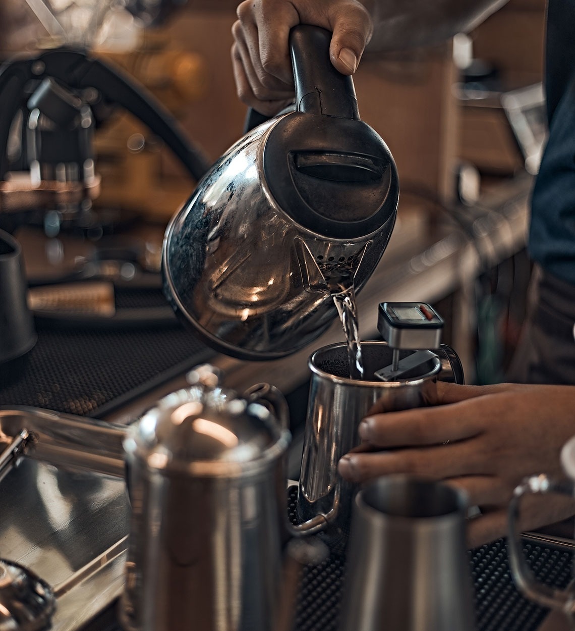 una persona está vertiendo agua de una tetera eléctrica en una taza