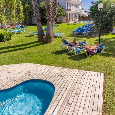 a woman sits on a lounge chair near a pool