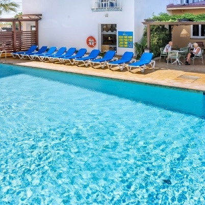 a swimming pool with chairs and tables in front of it