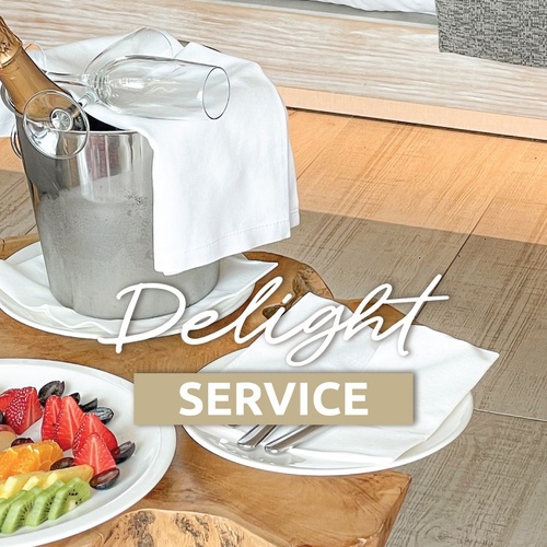 a bucket of champagne sits on a wooden table next to plates of fruit