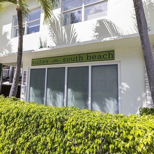a white building with a green sign that says suites at south beach