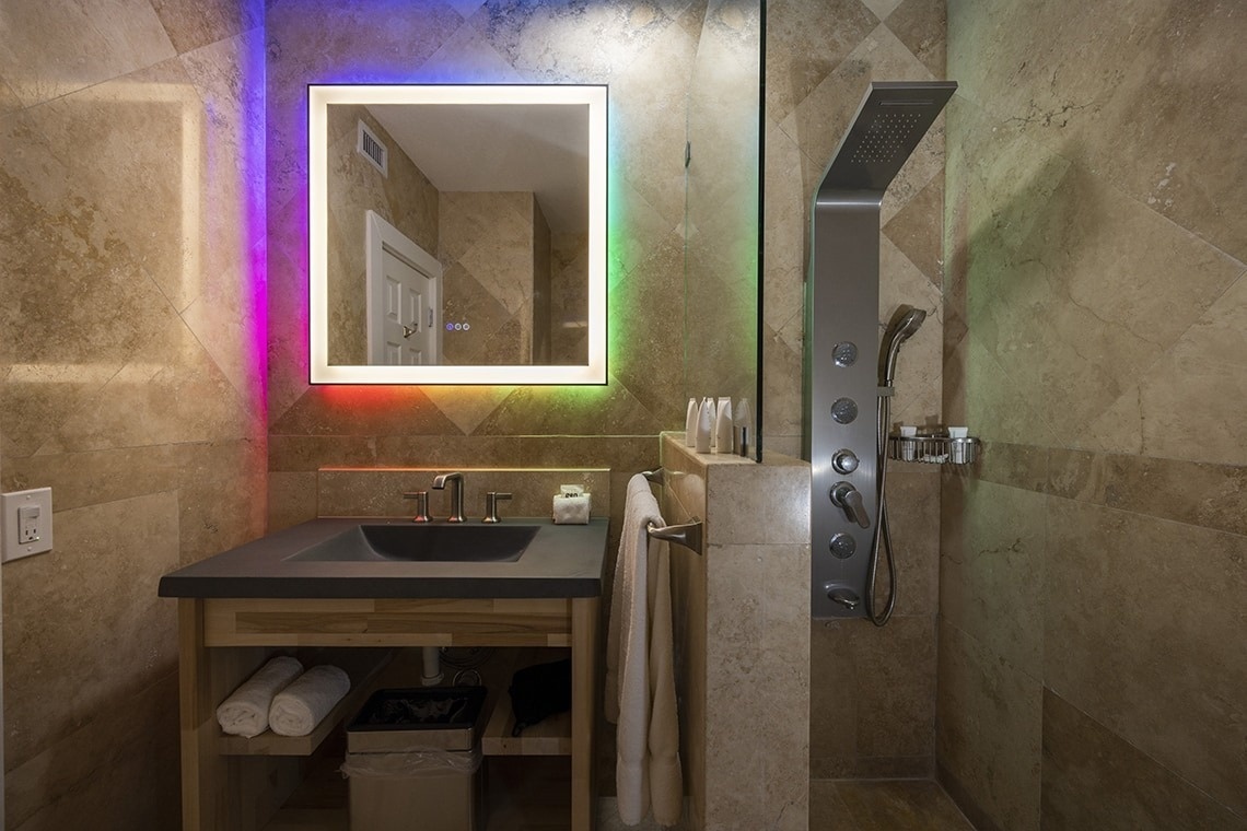 a bathroom with a rainbow lighted mirror above the sink