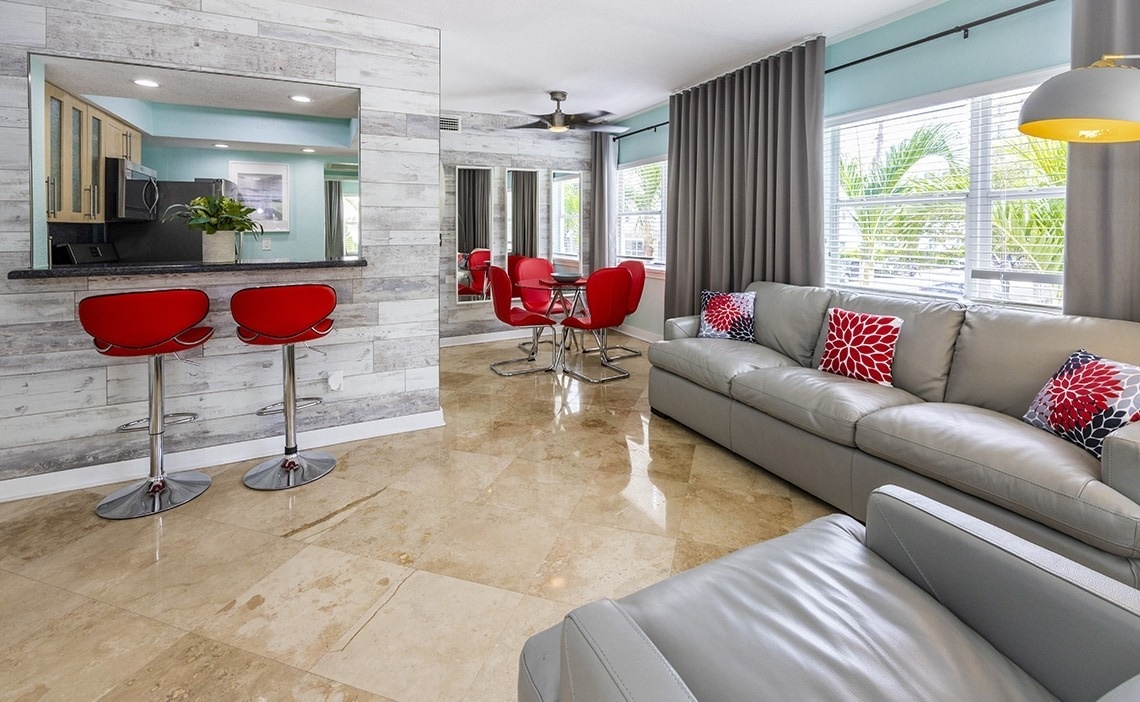 a living room with a grey couch and red chairs