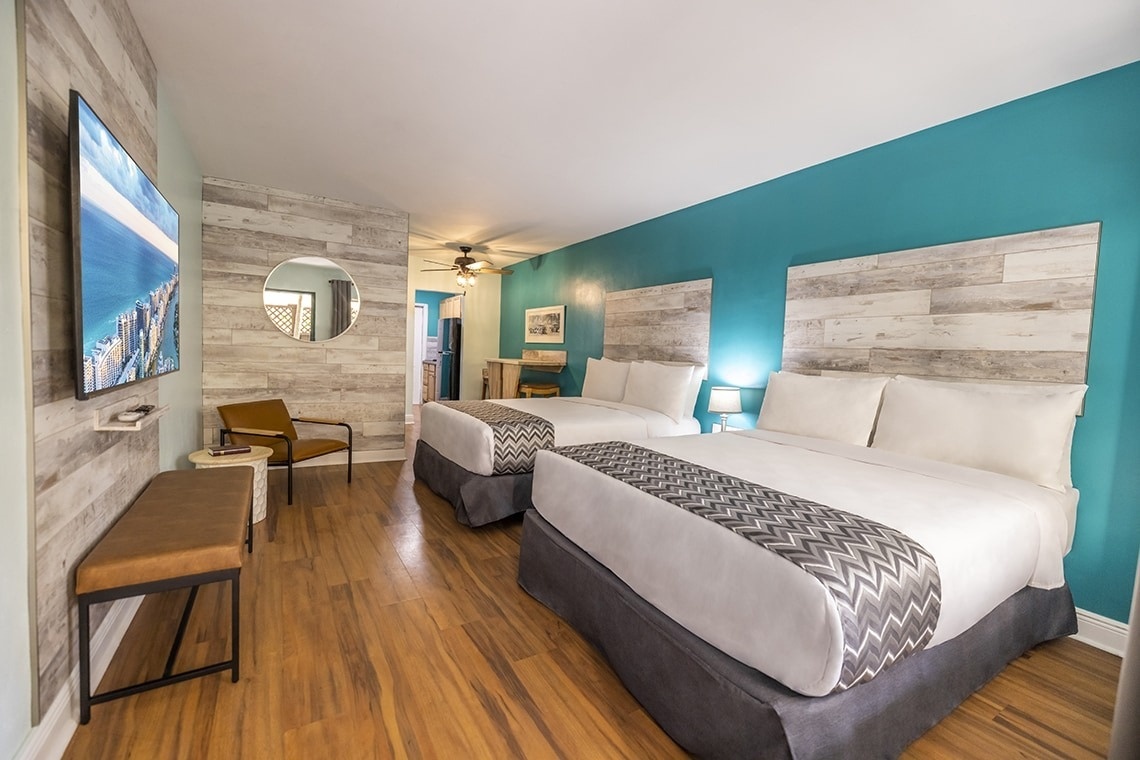 a hotel room with two beds and a flat screen tv