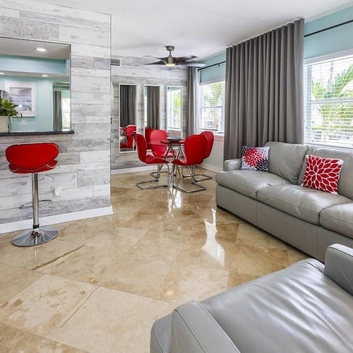 a living room with a grey couch and red chairs