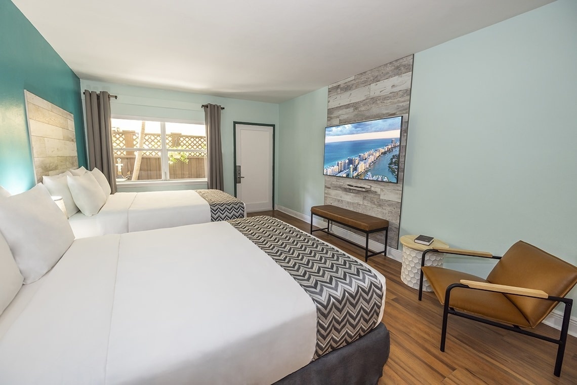 a hotel room with two beds and a flat screen tv