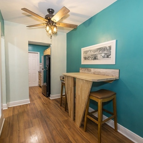 a hallway with a table and stools and a ceiling fan