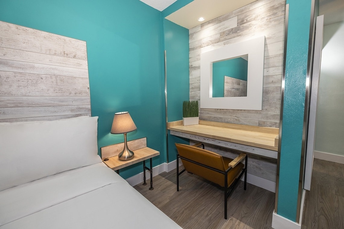 a bedroom with a desk and a mirror on the wall