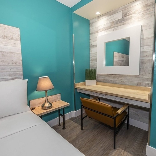 a bedroom with a desk and a mirror on the wall