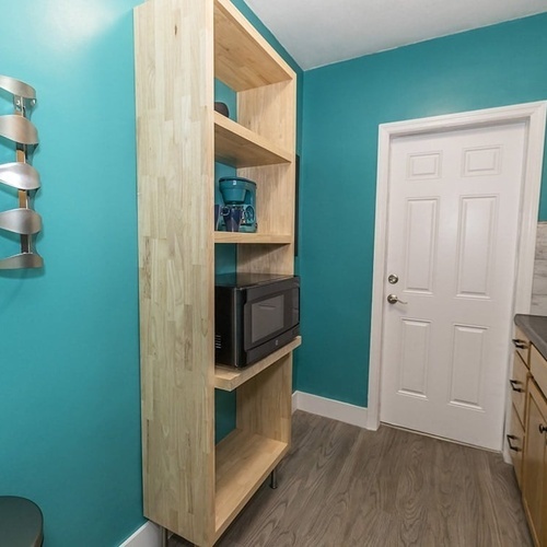 a wooden shelf with a microwave on top of it