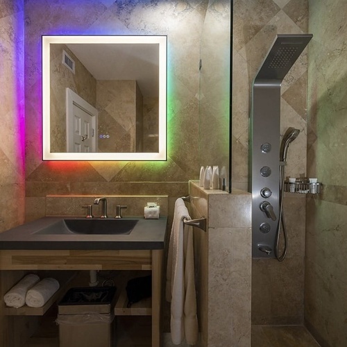 a bathroom with a rainbow lighted mirror and a sink
