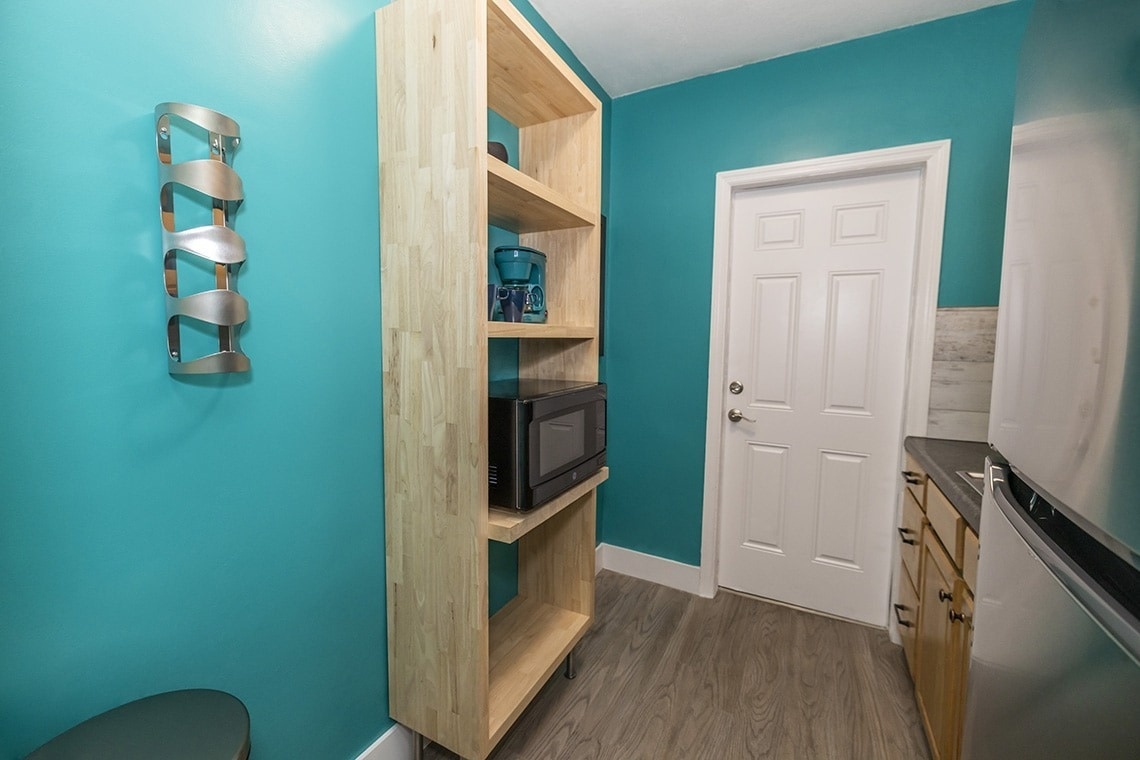 a wooden shelf with a microwave on top of it
