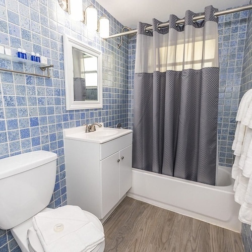 a bathroom with blue tiles and a gray shower curtain