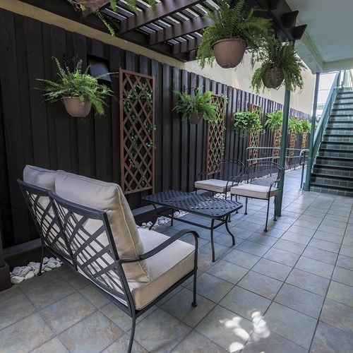 a patio area with a couch and chairs and potted plants