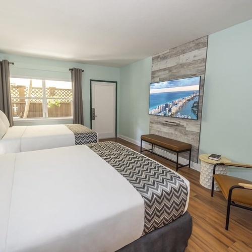 a hotel room with two beds and a flat screen tv