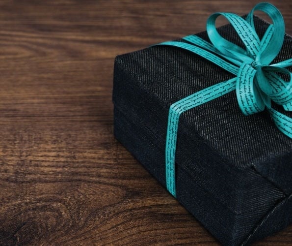 una caja de regalo negra con una cinta azul sobre una mesa de madera