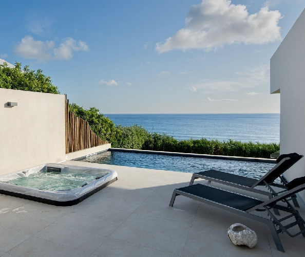 a hot tub sits next to a swimming pool overlooking the ocean