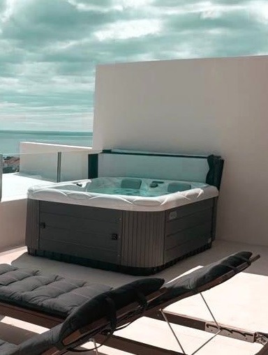 Jacuzzi no terraço do hotel com vista para o mar e espreguiçadeiras