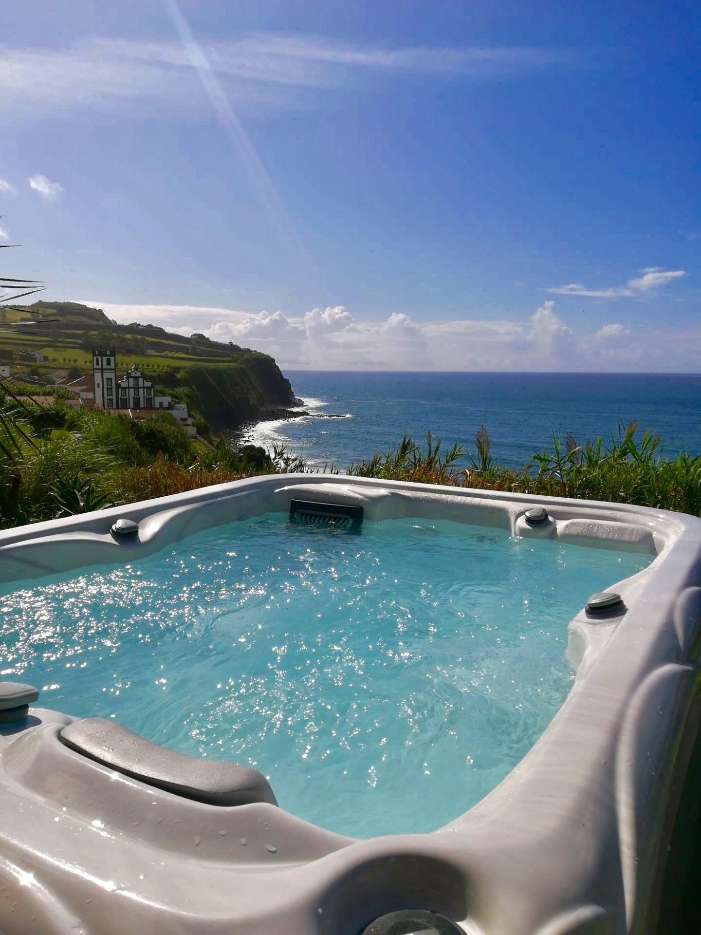 Relaxe no jacuzzi exterior do hotel com vista para o oceano, falésias e paisagem costeira.