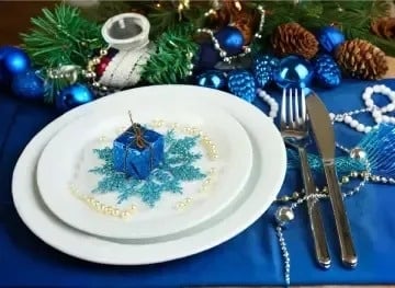 una mesa de navidad con platos , cubiertos y una caja de regalo azul .