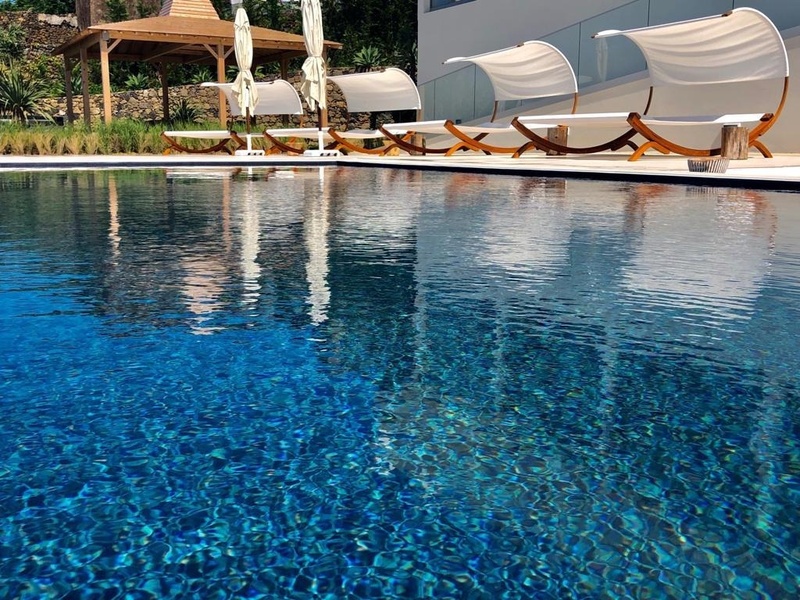 Sillas lounge junto a la piscina cristalina de Sul Villas & Spa.