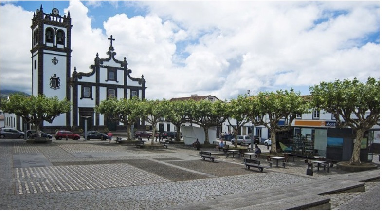 Town square with Sul Villas & Spa hotel, church, and trees in Azores, Portugal.