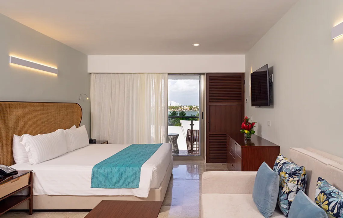 Sunset Royal Beach Resort hotel room with king bed and ocean view balcony.