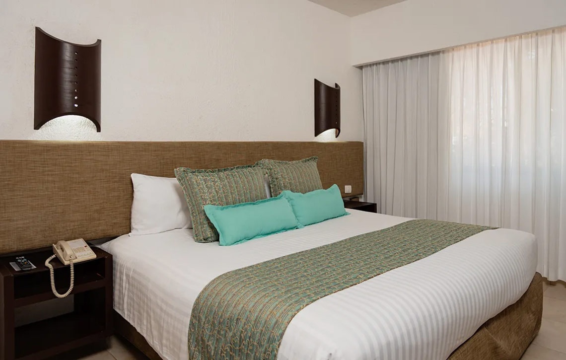Laguna Suites: Cama matrimonial con decoración moderna, lámparas de pared y cortinas.