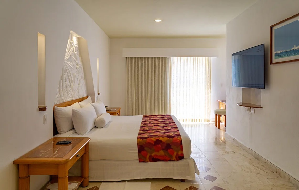 Habitación en Sunset Fishermen Beach Resort | Cama confortable, TV y balcón.