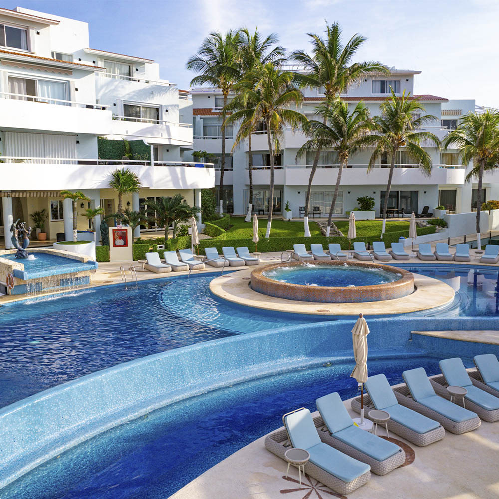 Luxurious resort pool area with lounge chairs and a hot tub. Sunset Hotels Collection: Corporativa
