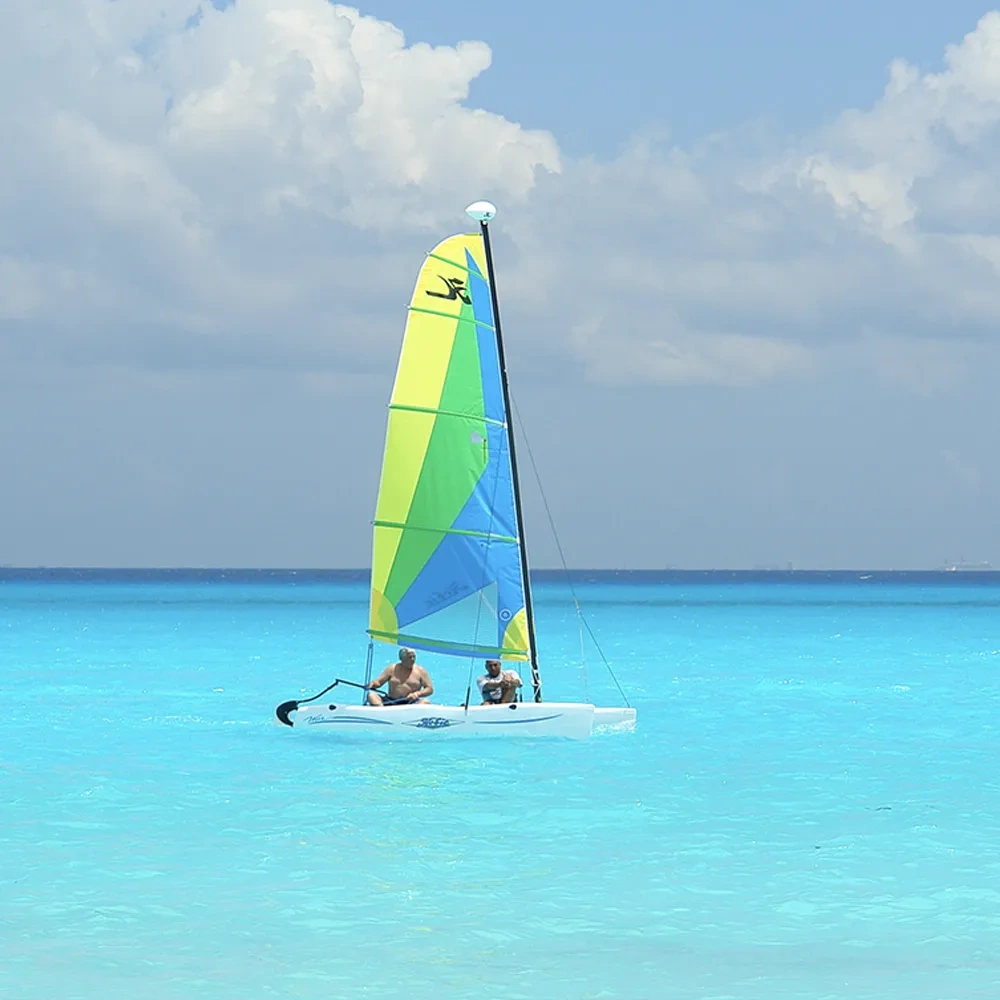 Catamarán con dos hombres navegando en aguas turquesas, una imagen para Sunset Hotels Collection: Corporativa.