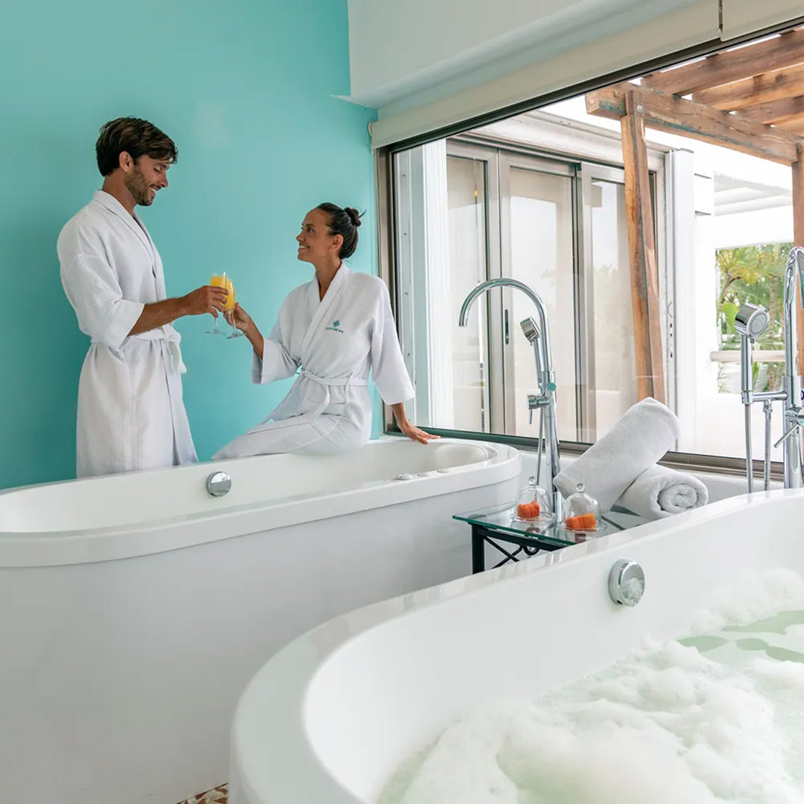 Pareja brindando con jugo en un baño de lujo en Sunset Marina Resort & Yacht Club.