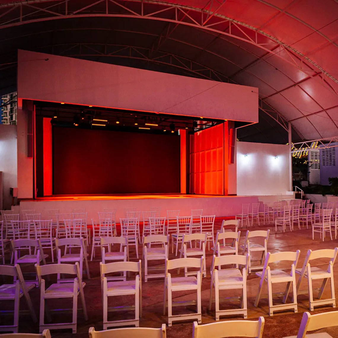 Outdoor stage at Sunset Royal Beach Resort with rows of white chairs.