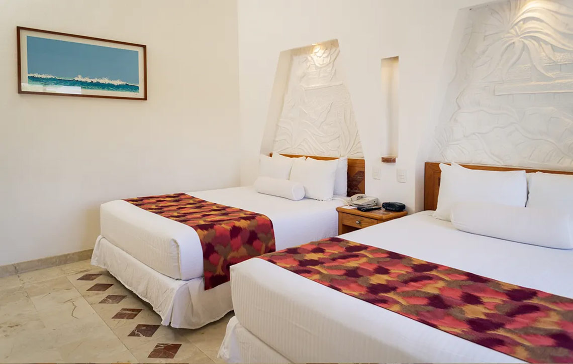 Habitación doble con decoración playera y cómoda ropa de cama en Sunset Fishermen Beach Resort.