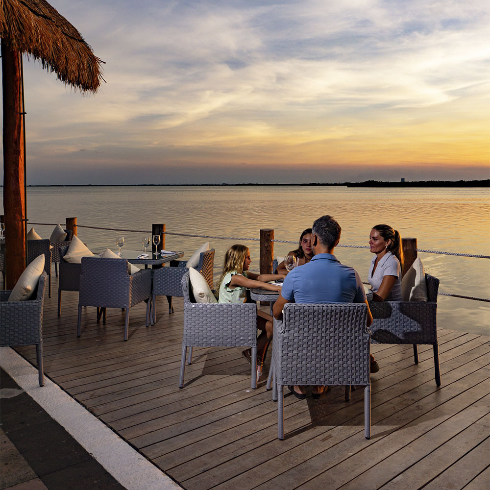 Restaurante frente al mar en Sunset World Resorts: Corporativa. Mesas, sillas y vista al océano.