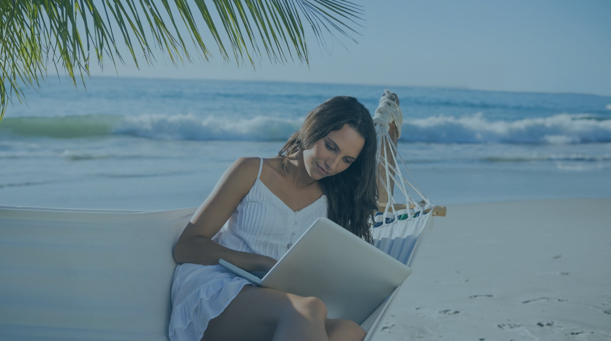 Woman working on laptop in hammock on beach Sunset Hotels Collection: Corporativa