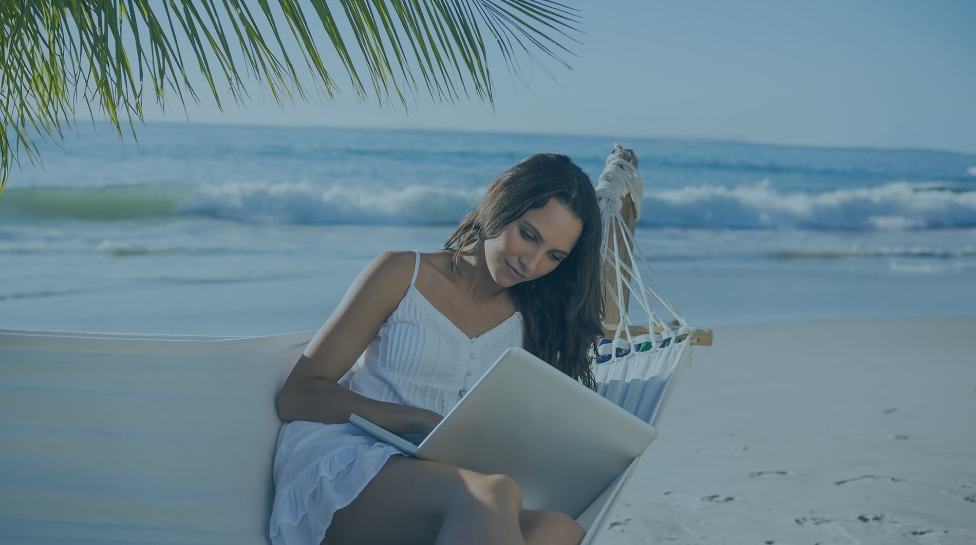 Woman working on laptop in hammock on beach, ocean view, ideal for Sunset Hotels Collection: Corporativa