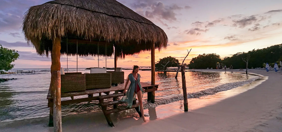 Sunset at Hacienda Tres Rios: Woman in kimono on pier overlooking calm ocean.
