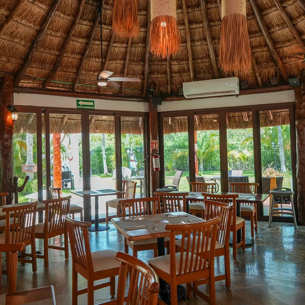 Restaurante con techo de paja en Sunset World Resorts: Corporativa, mesas listas.