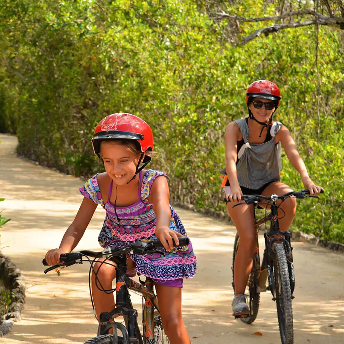 Two guests cycling on a sandy path at Hacienda Tres Rios, enjoying the lush surroundings.