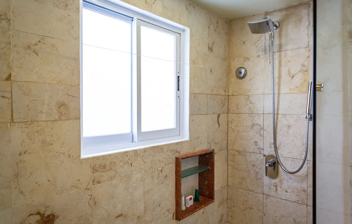 Ducha de mármol y ventana en Sunset Fishermen Beach Resort.