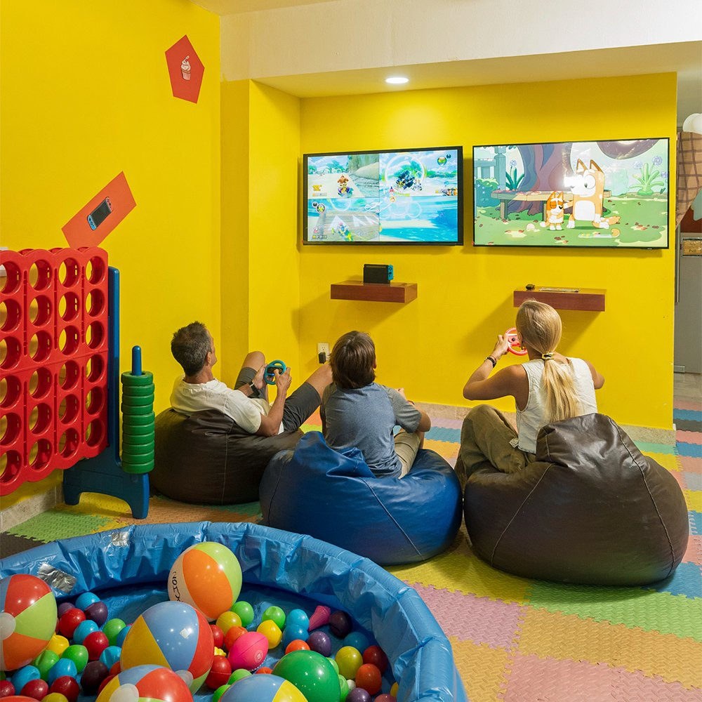 Adultos y niños disfrutan en Sunset World Resorts: Corporativa sala de juegos.