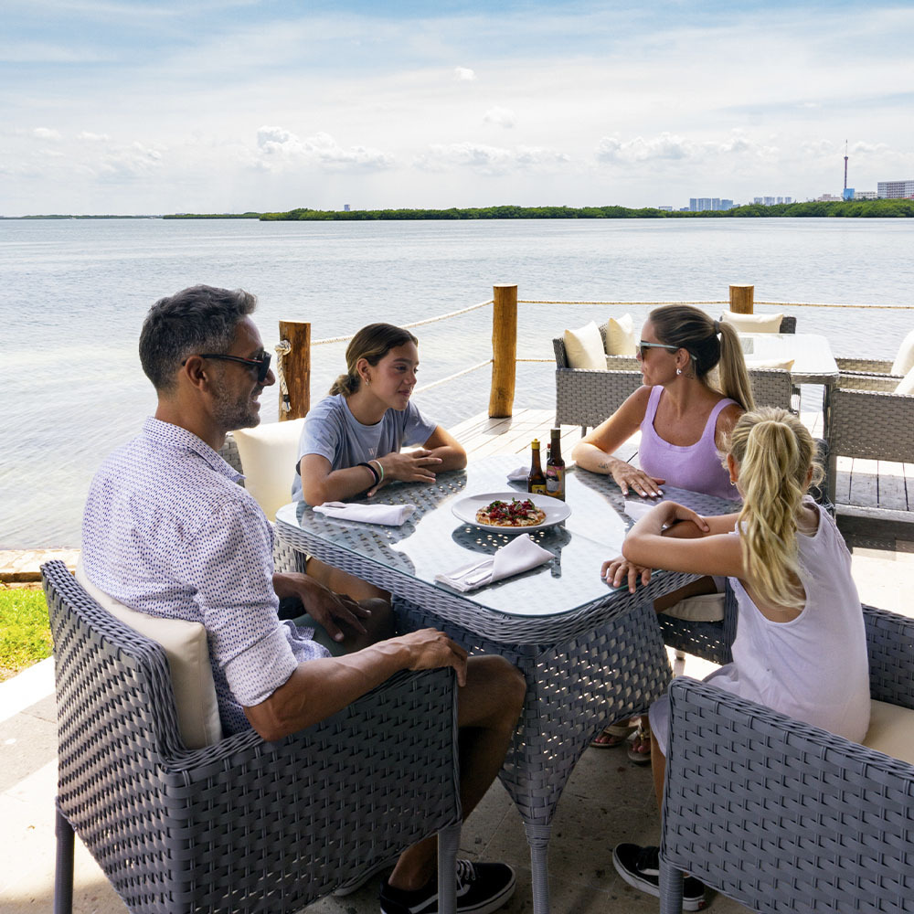 Familia disfrutando comida al aire libre en un resort. Sunset Hotels Collection: Corporativa.